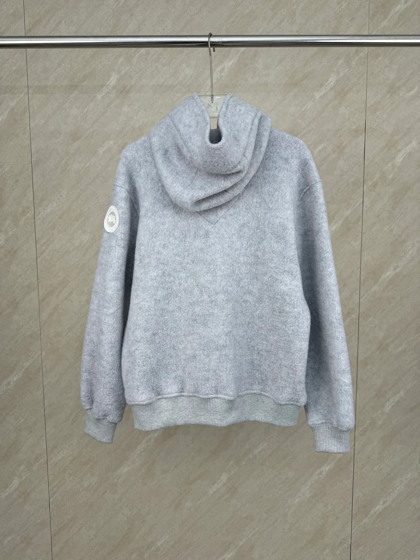 P810 Canada Goos Fleece Badge Hooded Jacket SIZE S/M/L/XL The fabric is made of wool as the main body, with a very small amount of spandex and polyester fiber blended into the wool fleece fabric. The sleeves and hem are closed with 2×2 ribbing. Its strong elasticity can closely fit wrists and waists of different thicknesses, forming an effective 'seal' to prevent cold wind from blowing back. It can still maintain its original shape after repeated stretching and use, and is not easy to loose and deform. And the ribbed cuffs can convey a sense of design and enhance the visual beauty.